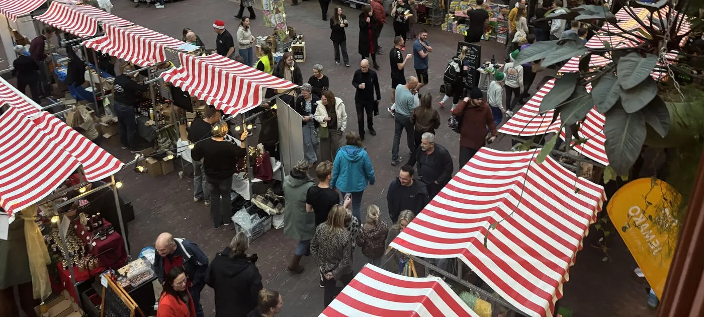 Marktkramen op een personeelskerstmarkt met medewerkers die langs de kramen lopen