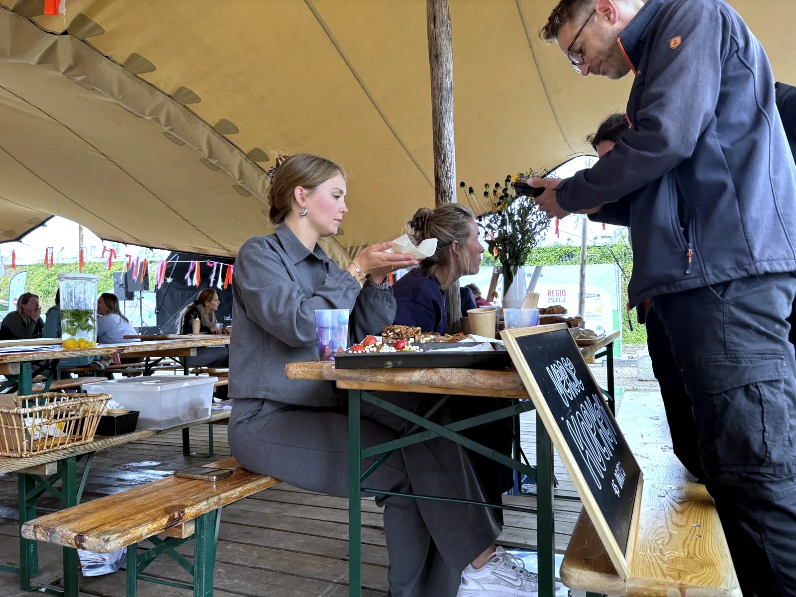 Een bezoeker rekent met de telefoon af bij een kraam op een buitenevenement